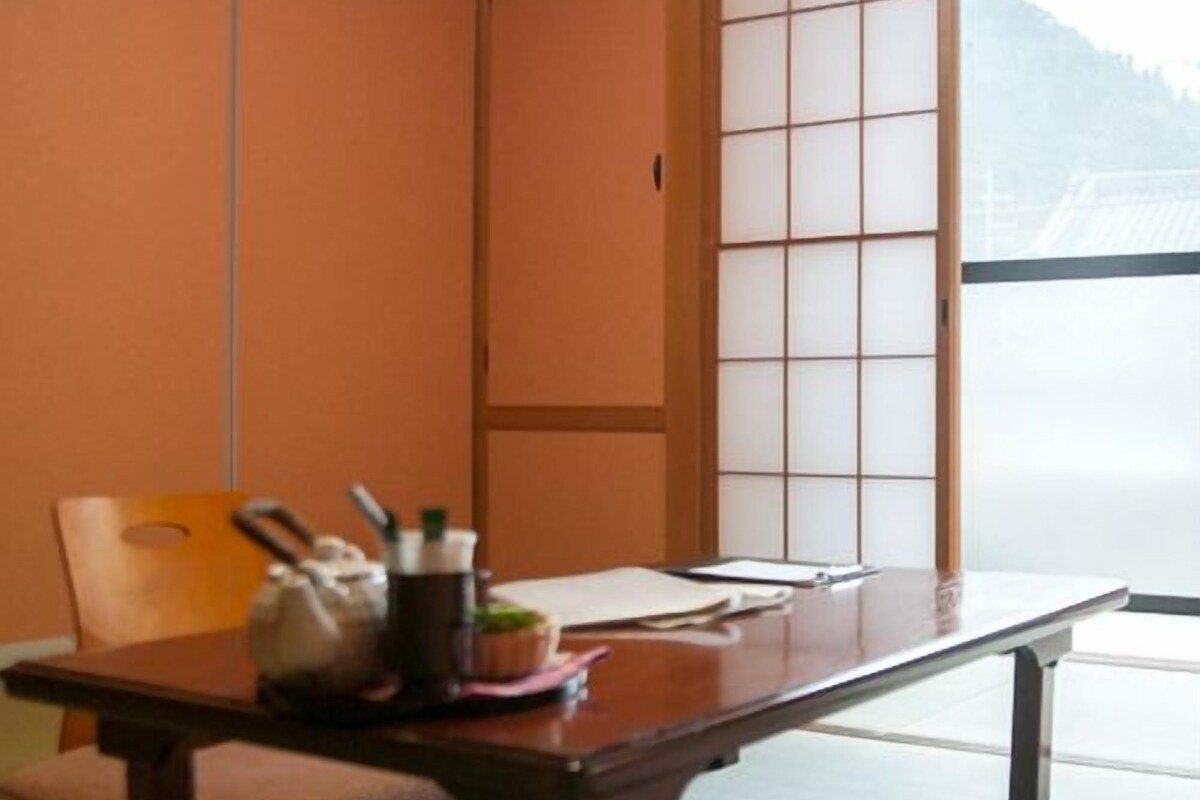 Una habitación japonesa tradicional con suelo de tatami, una mesa de madera baja y una puerta corrediza estilo shoji.