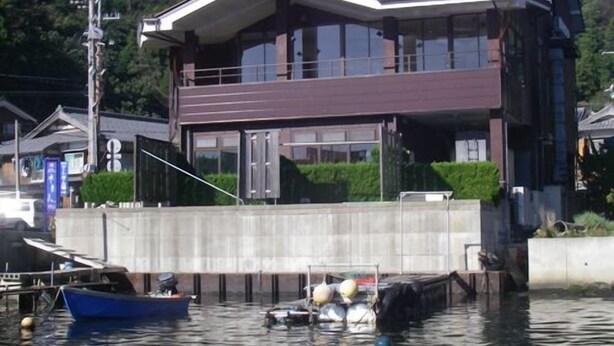 Un immeuble de deux étages à l’architecture moderne, situé près d’une étendue d’eau où sont amarrés des bateaux.