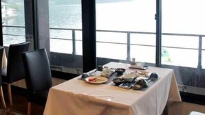 Un coin repas avec une table dressée pour deux personnes, donnant sur un plan d’eau.