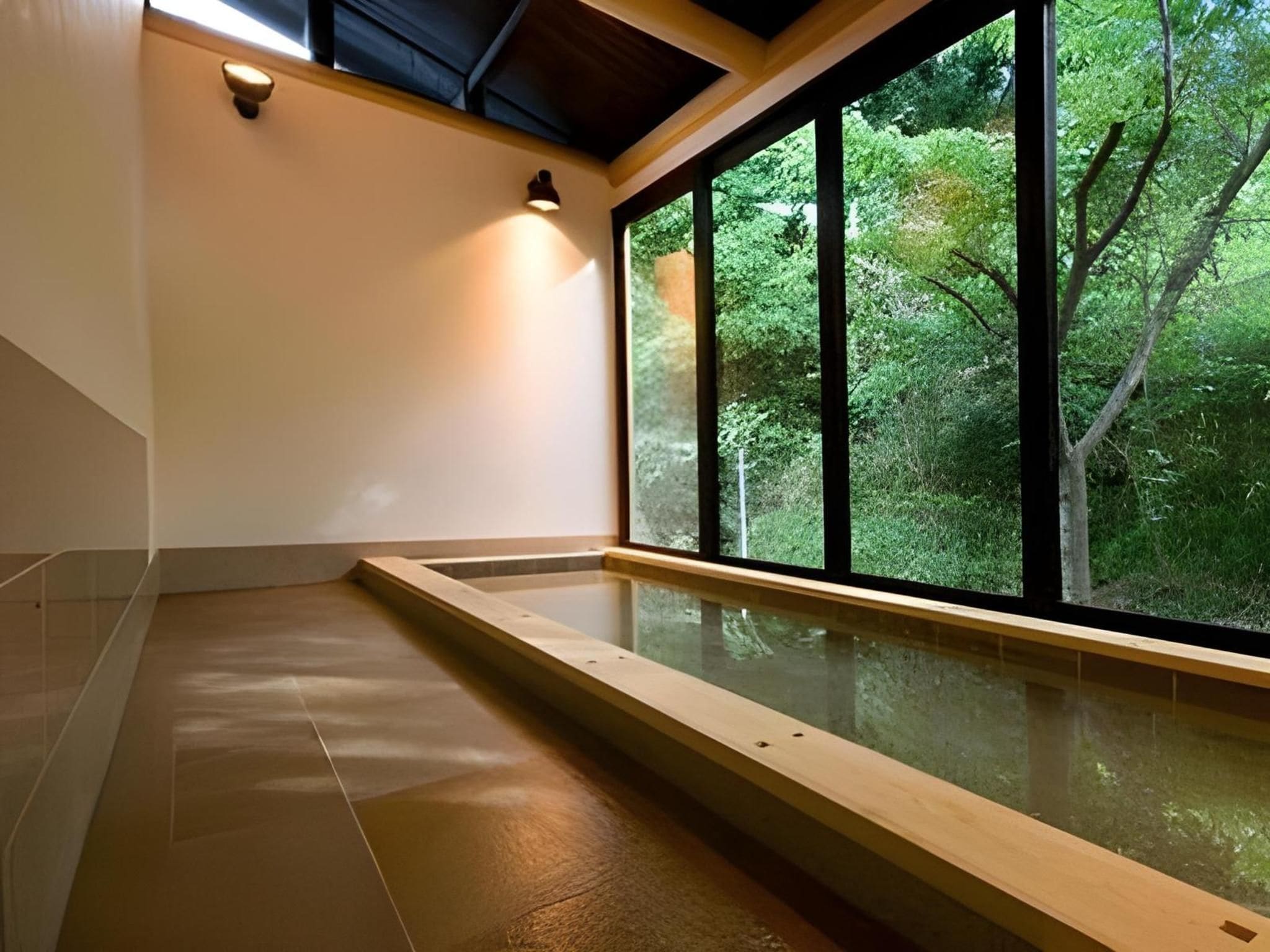 Een wellnessruimte met een houten bank, een glazen omheining en uitzicht op een bos door grote ramen.