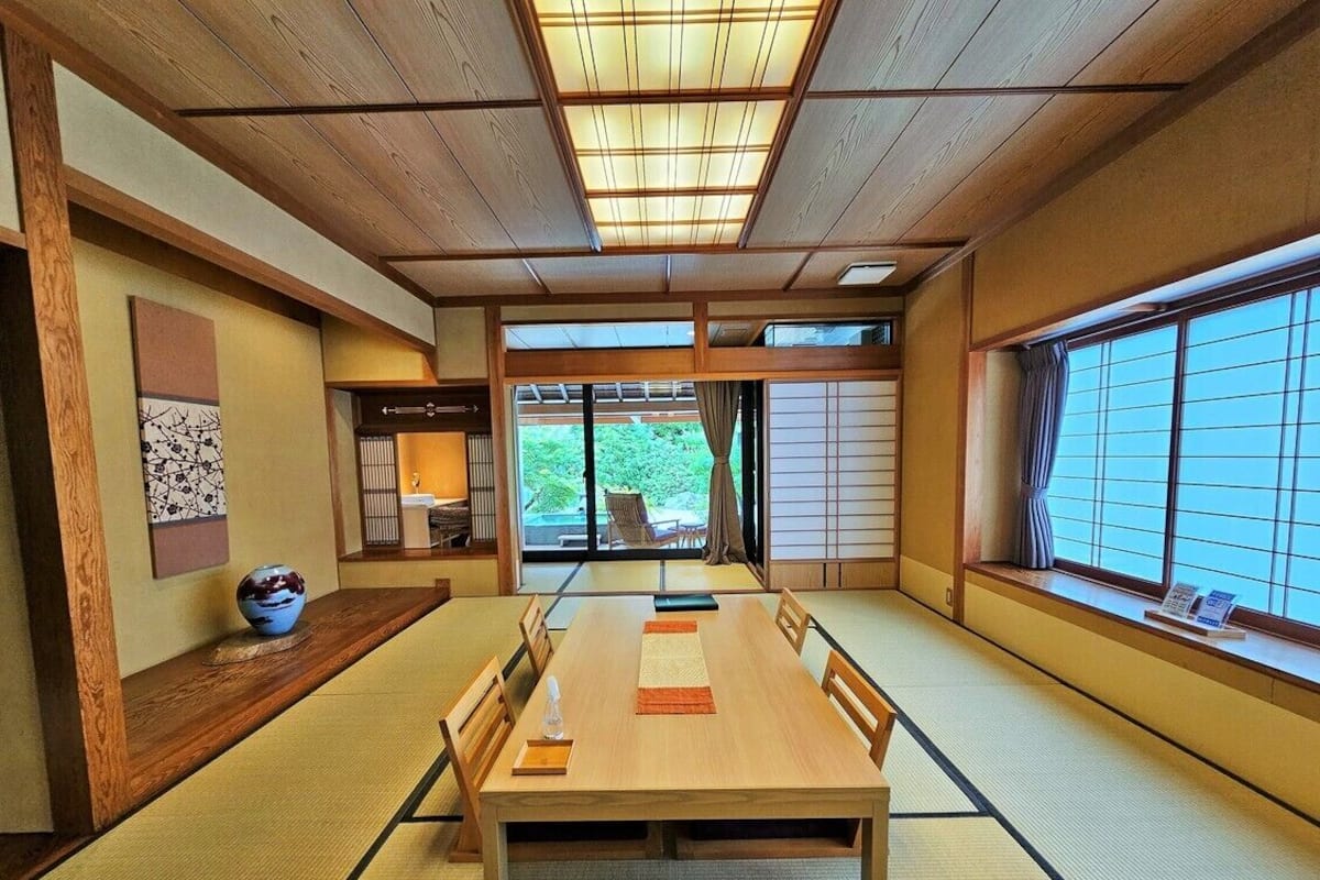 A traditional Japanese room with tatami flooring, a wooden table, and sliding doors.