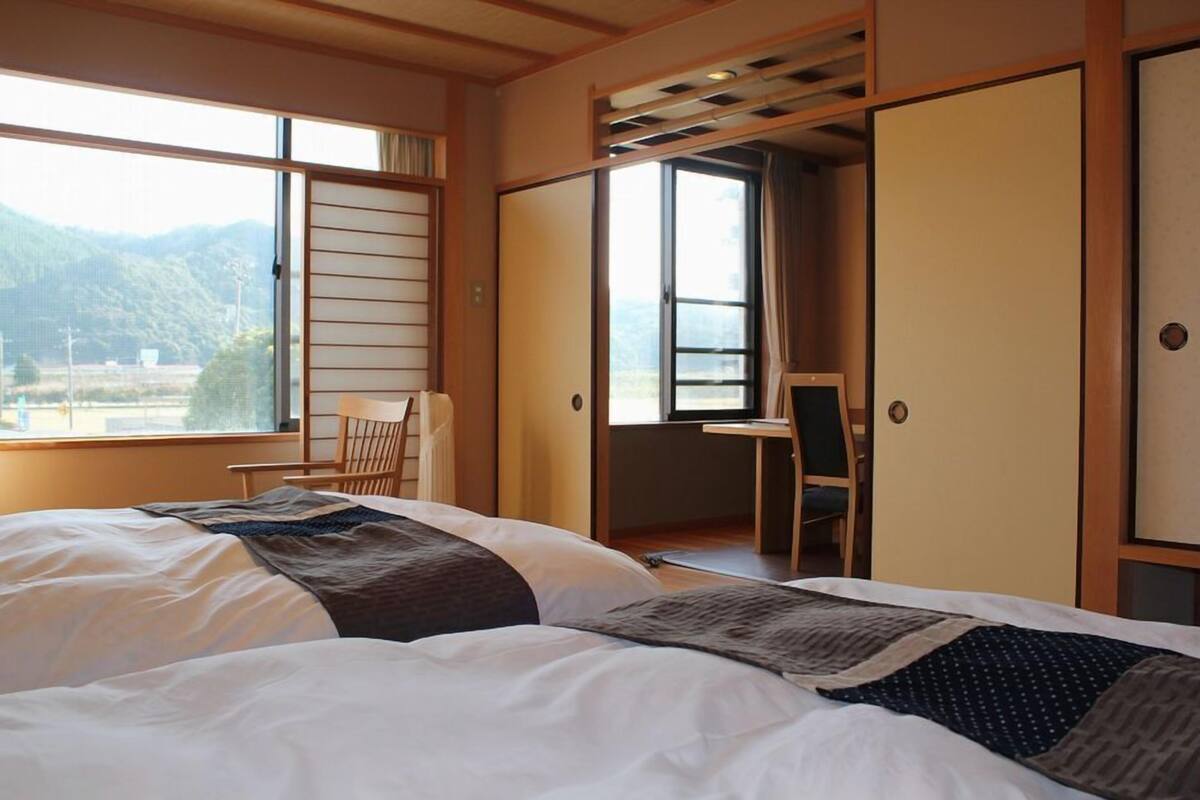 A room with a bed, a desk, and a view of the outdoors.