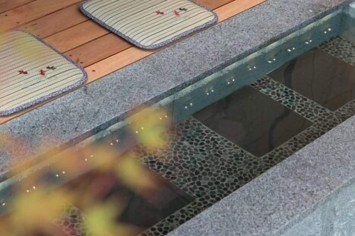 A wooden deck with stone steps leading to a water feature.