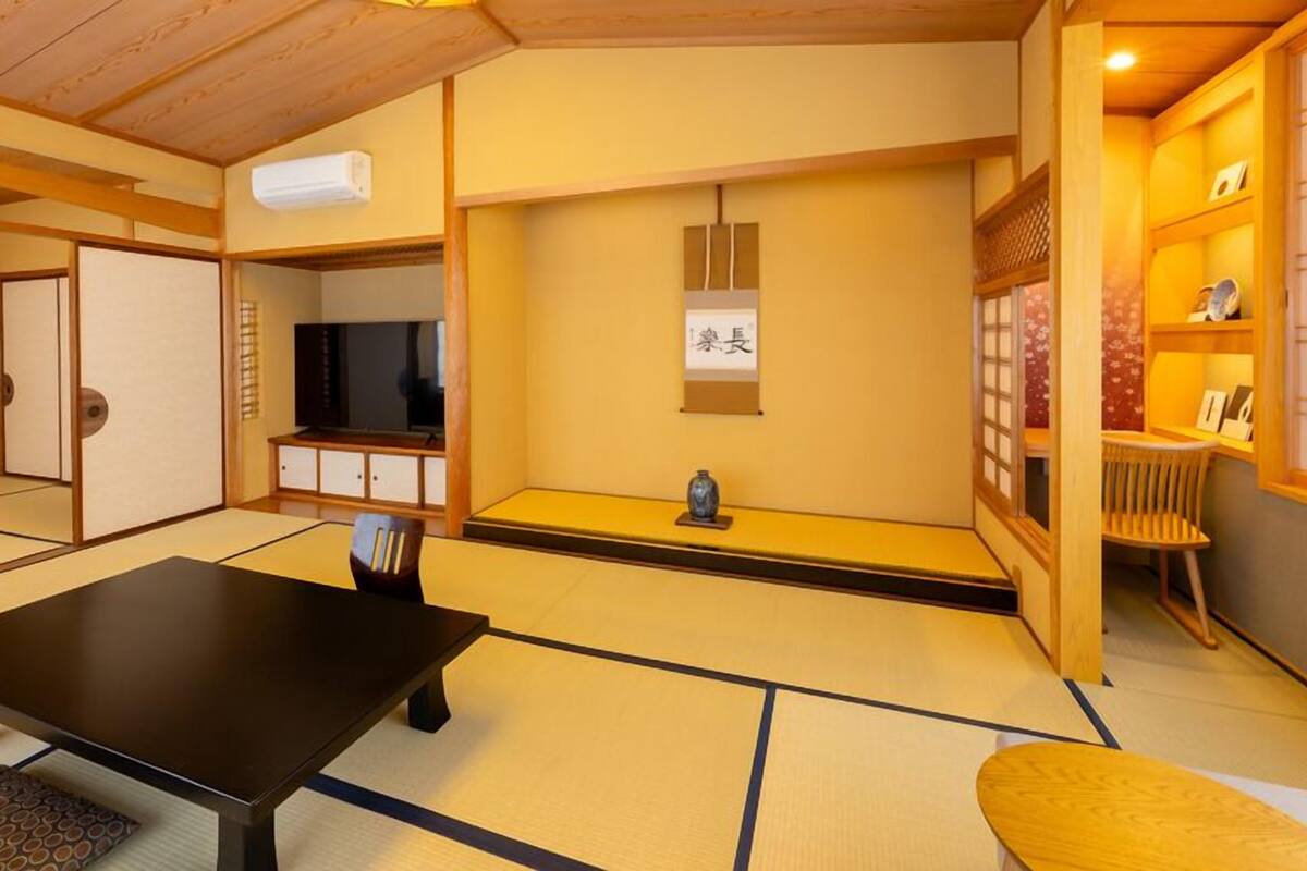 A tatami mat room with a black table, a TV, and a shelf with items.