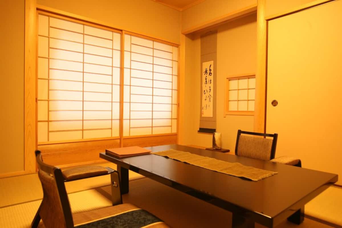 A traditional Japanese room with tatami flooring, a low table, and sliding doors.