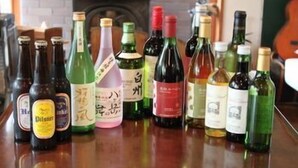 On peut voir différentes bouteilles disposées sur une surface en bois, probablement dans un bar ou un espace dédié à la dégustation.