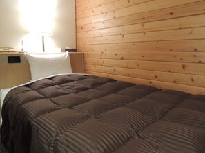 Ein Einzelbett mit einer braunen Steude, einem Holz-Kopfteil und einem Nachttisch mit Lampe.