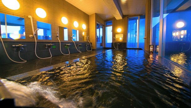 A series of indoor hot tubs with multiple faucets and mirrors, surrounded by wooden walls and large windows. - Hotel Meijiya (Hamamatsu)