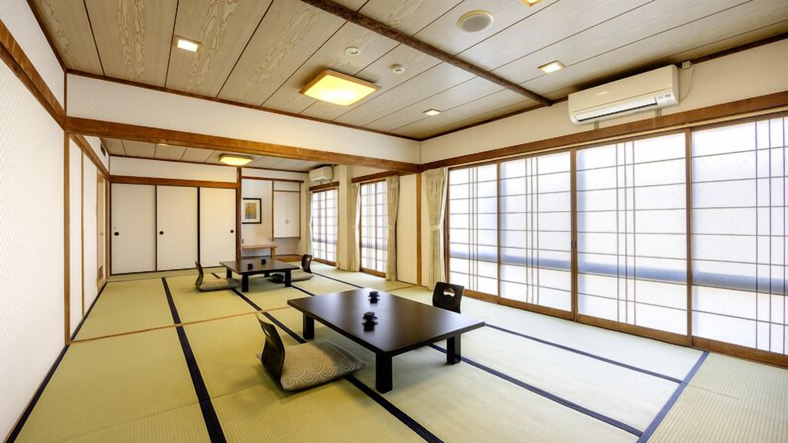 Una habitación japonesa tradicional con suelo de tatami, puertas correderas y bajo techo con iluminación empotrada.