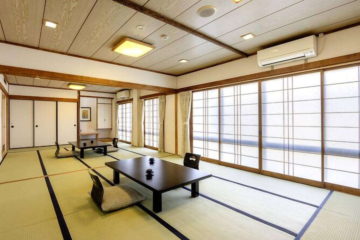 A traditional Japanese room with tatami flooring, sliding doors, and a low ceiling with recessed lighting.