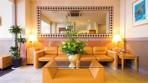 A lobby with a large mirror, two sofas, a coffee table, and two lamps. - Hotel Meijiya (Hamamatsu)