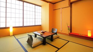 A traditional Japanese room with tatami flooring, a low table with a tea set, a cushion, and a shoji screen. - Hotel Meijiya (Hamamatsu)