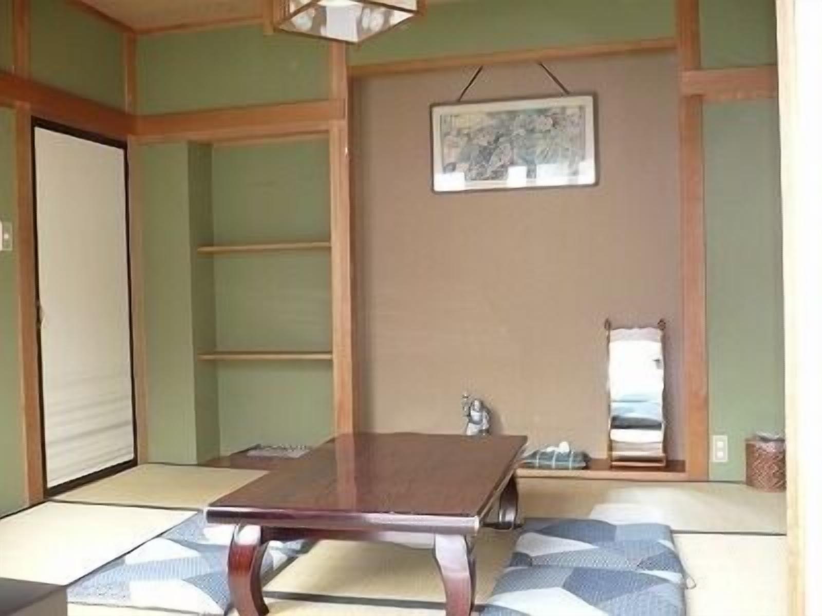 Ein traditioneller japanischer Raum mit Tatami-Boden, einem niedrigen Holztisch und einem hängenden Bild.