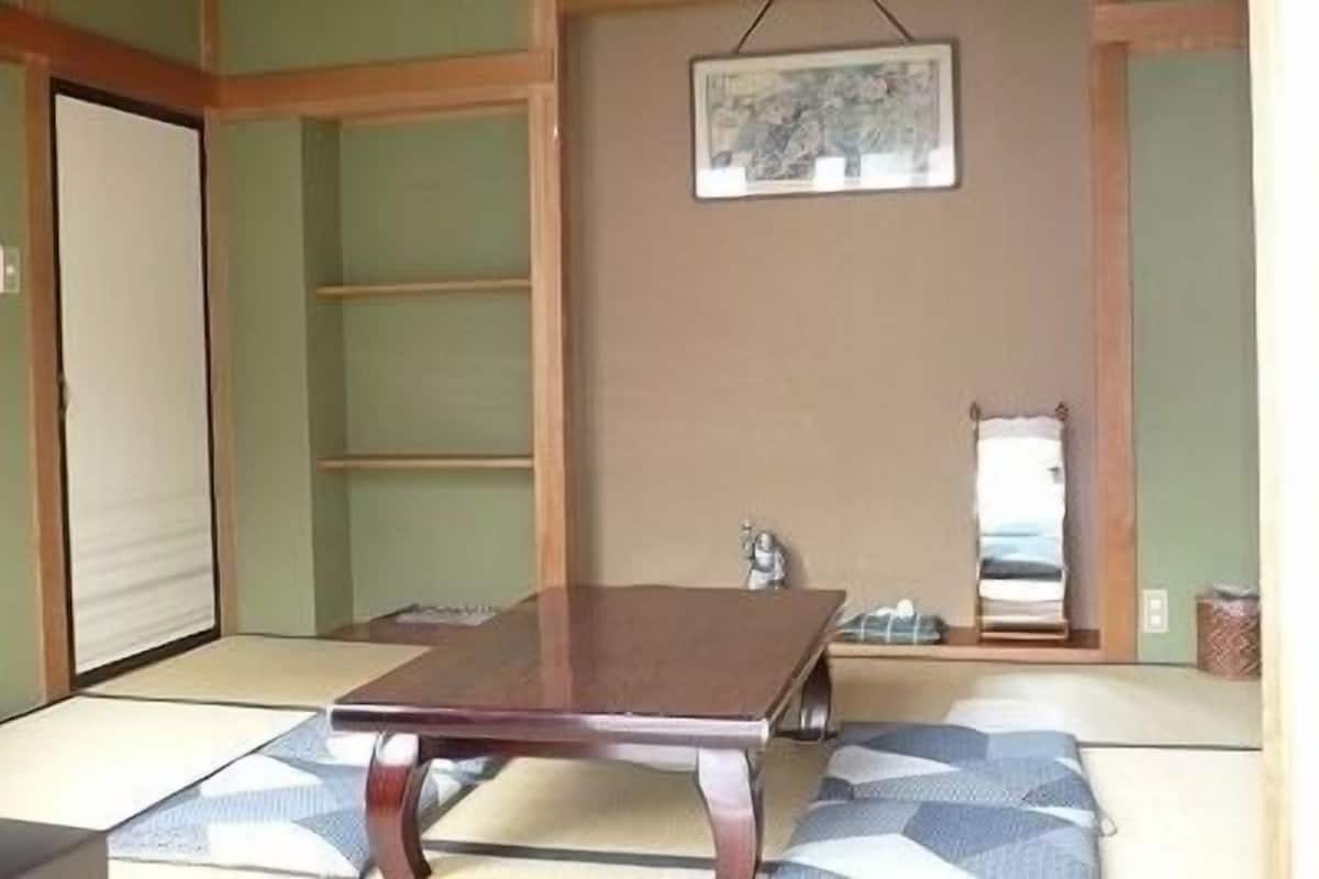 Una habitación japonesa tradicional con suelo de tatami, una mesa de madera baja y un cuadro colgado.