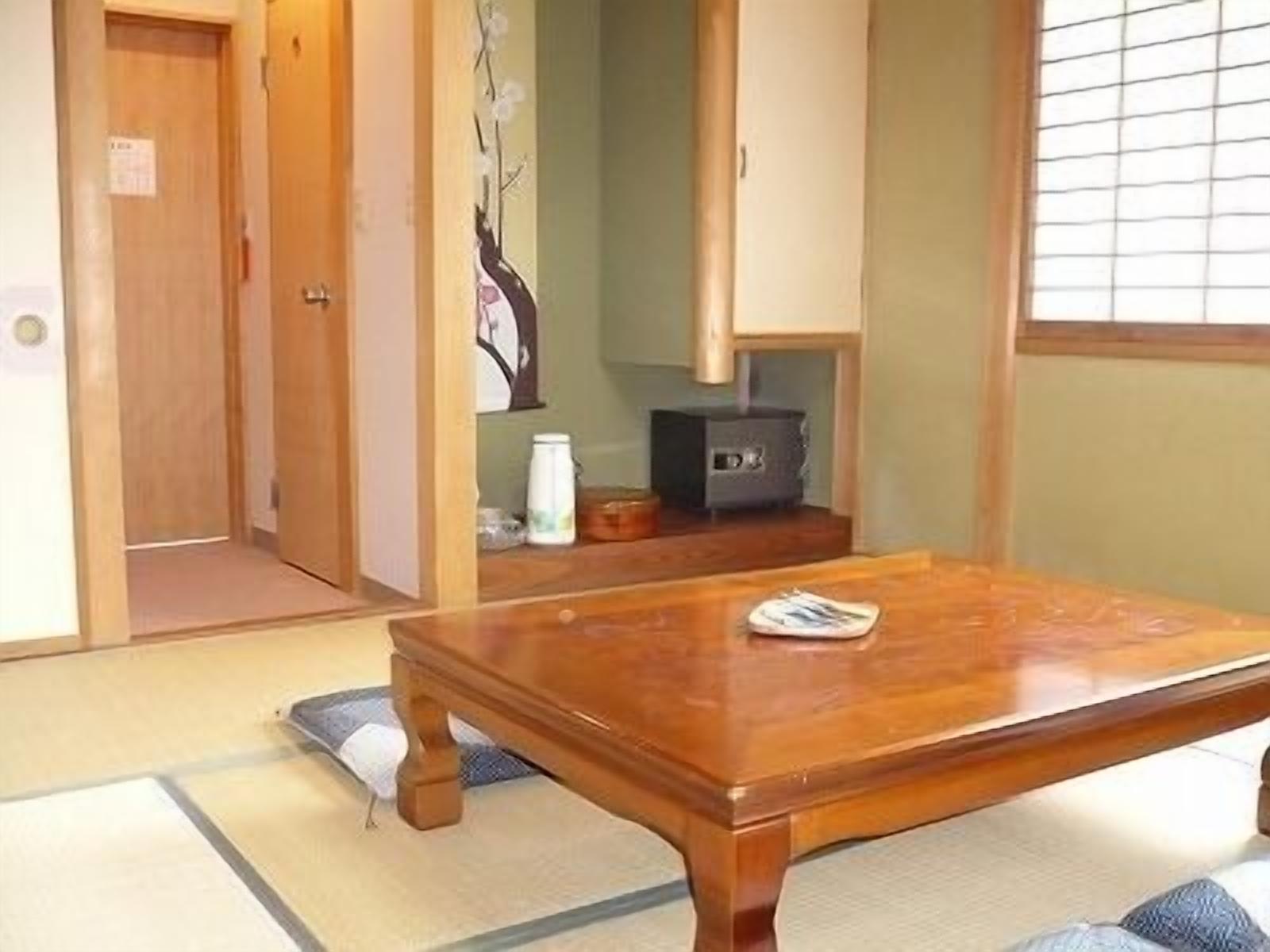 Ein traditioneller japanischer Raum mit Tatami-Böden, einem Holztisch, einem niedrigen Schrank und einer Schiebetür.