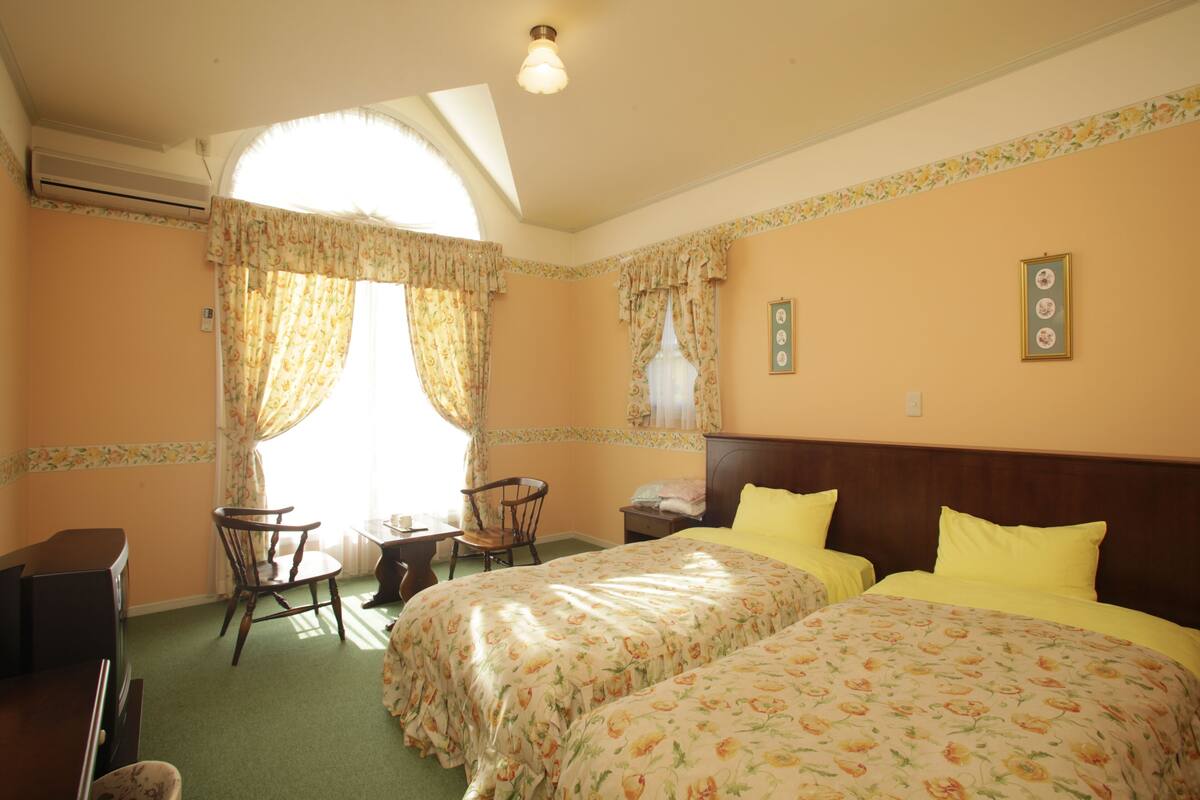 A room with two beds, a desk, and a chair.