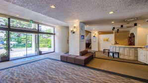 A reception area with a sofa, a counter, and a view of the outdoors. - Hotel Green Plaza Hamanako (Hamamatsu)