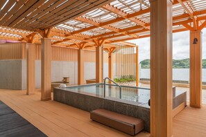A wooden deck with a hot tub, seating area, and a view of a body of water. - Hotel Green Plaza Hamanako (Hamamatsu)