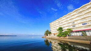 A waterfront hotel with multiple balconies, a calm sea, and clear skies. - Hotel Green Plaza Hamanako (Hamamatsu)
