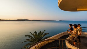 A coastal view with a calm sea, a palm tree, and a group of people on a balcony. - Hotel Green Plaza Hamanako (Hamamatsu)