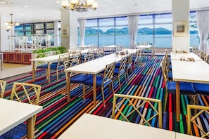 Un comedor con mesas y sillas, una alfombra estampada y vista al agua.