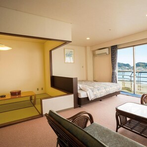 A hotel room with a bed, a dining table, a chair, a small table with a bowl, a picture on the wall, and a view of the sea. - Hotel Green Plaza Hamanako (Hamamatsu)