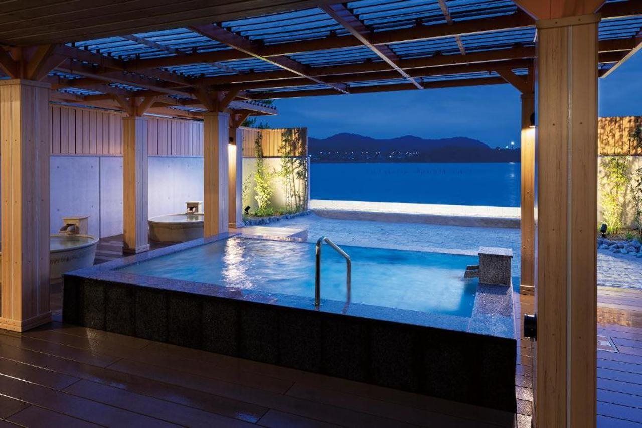 A hot tub area with a view of the sea and mountains at dusk.