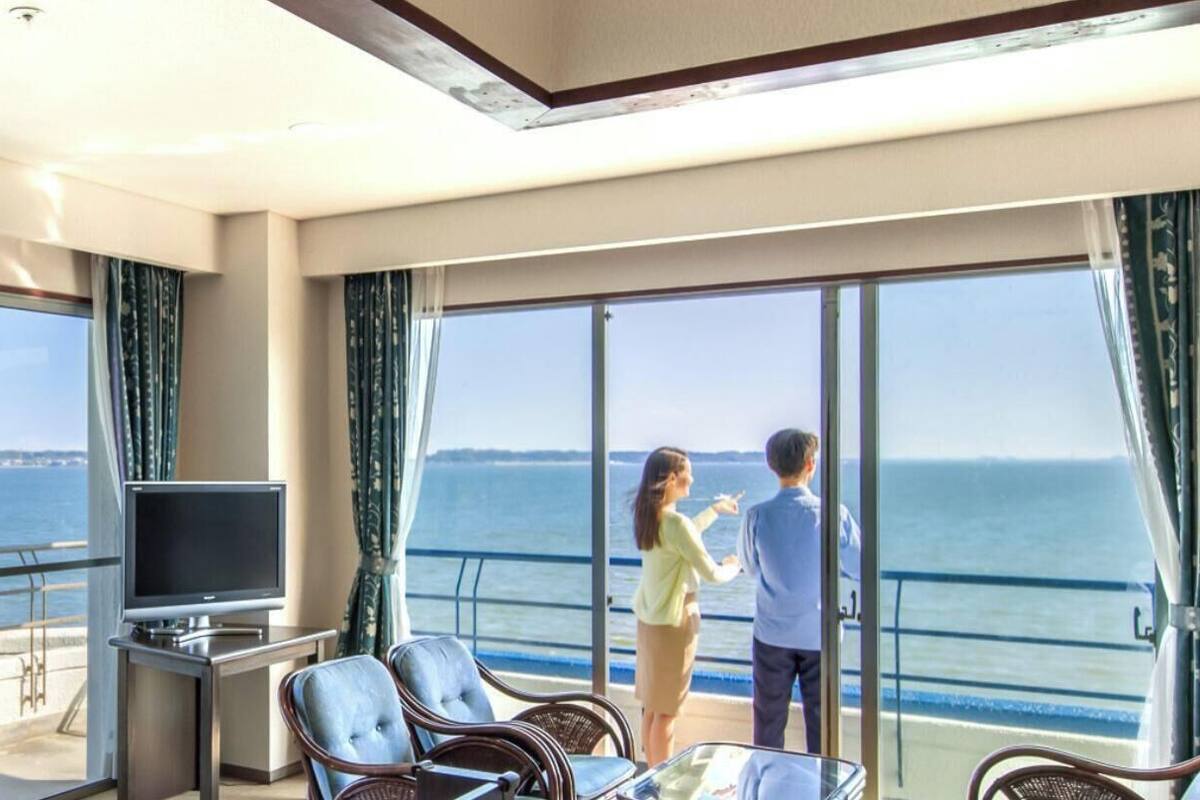 A balcony with a TV, seating, and a view of the sea.