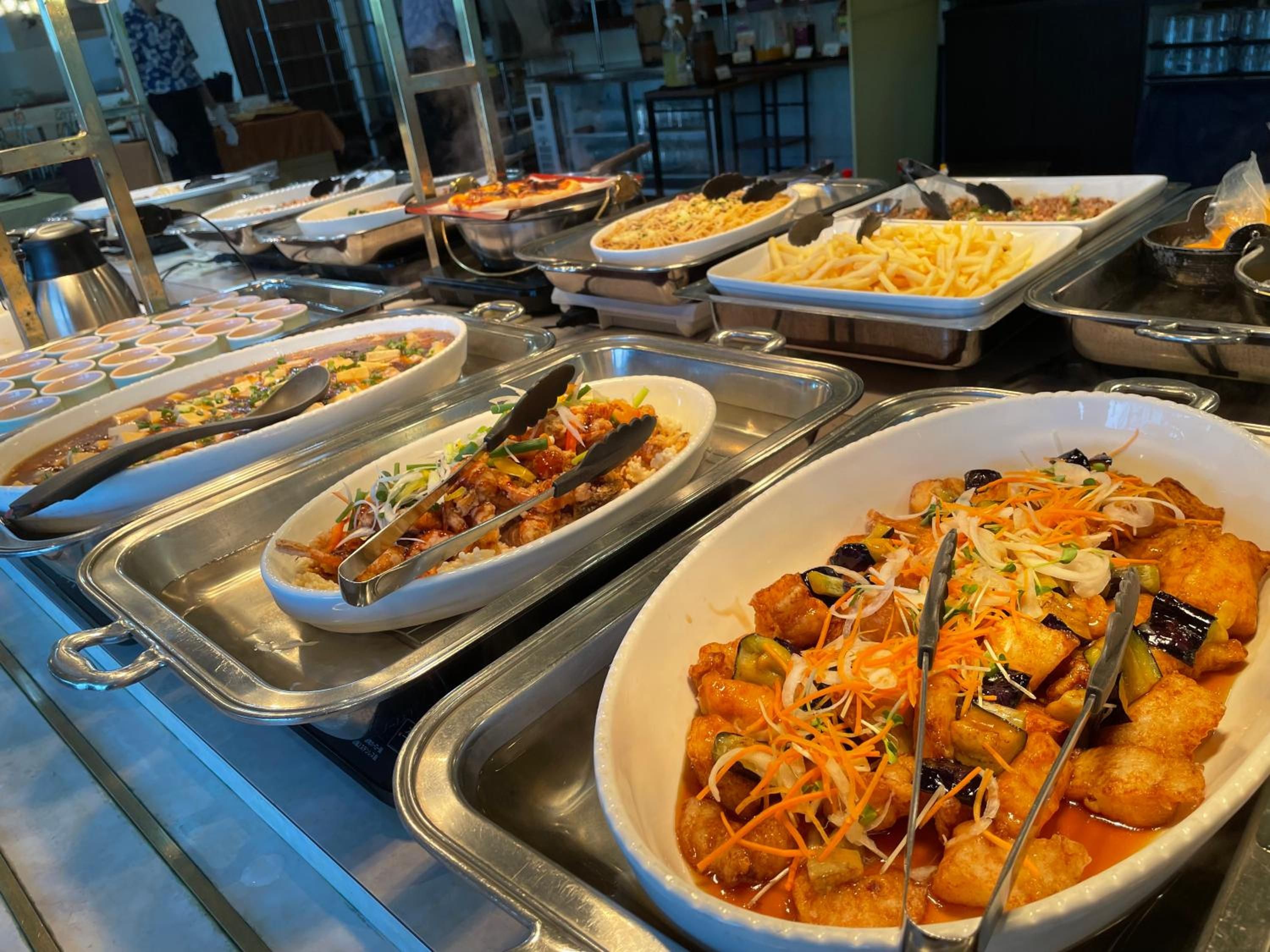 A buffet with various dishes including pasta, rice, and a dish with vegetables and meat.