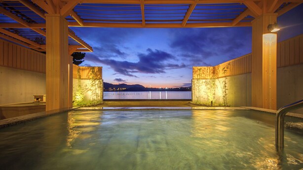 An indoor swimming pool with a view of a body of water and mountains at dusk. - Hotel Green Plaza Hamanako (Hamamatsu)
