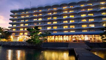 A multi-story hotel with balconies, a pool, and a waterfront view.