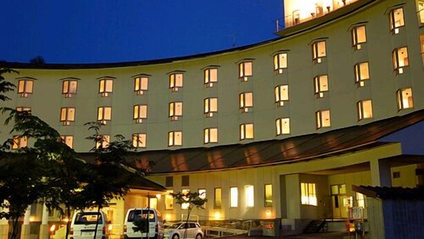 A hotel with a curved facade, multiple windows, and a sign in a foreign language. - Zao Onsen Zao Shiki No Hotel (Yamagata)