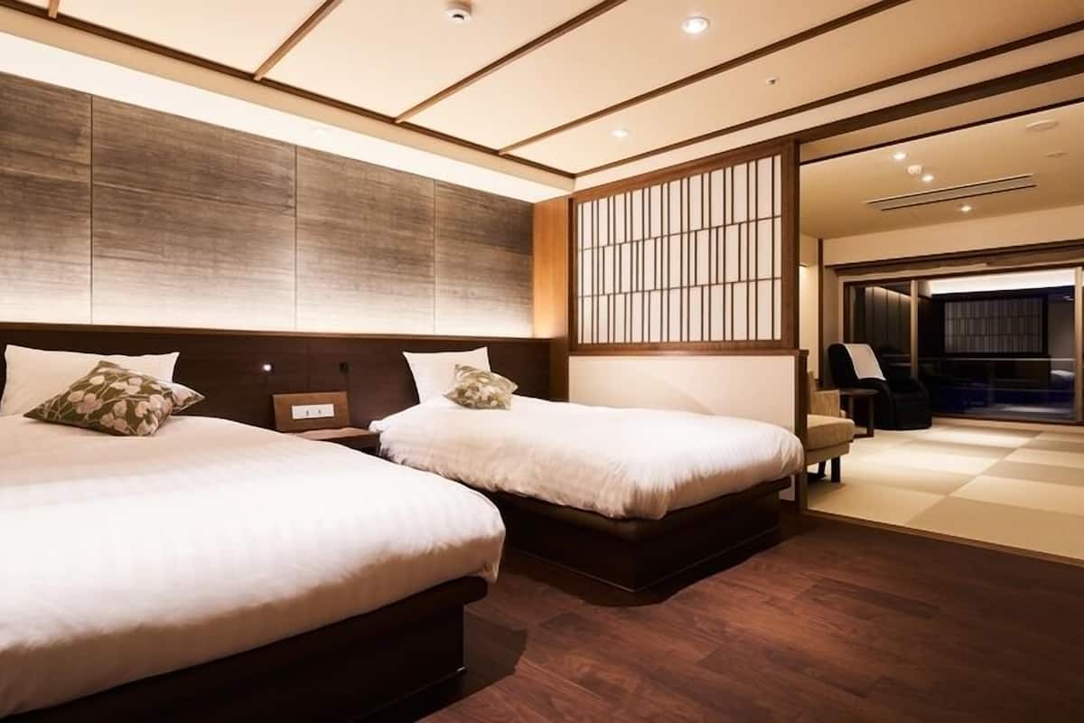 A hotel room with two beds, a large window, and a view of the outside.