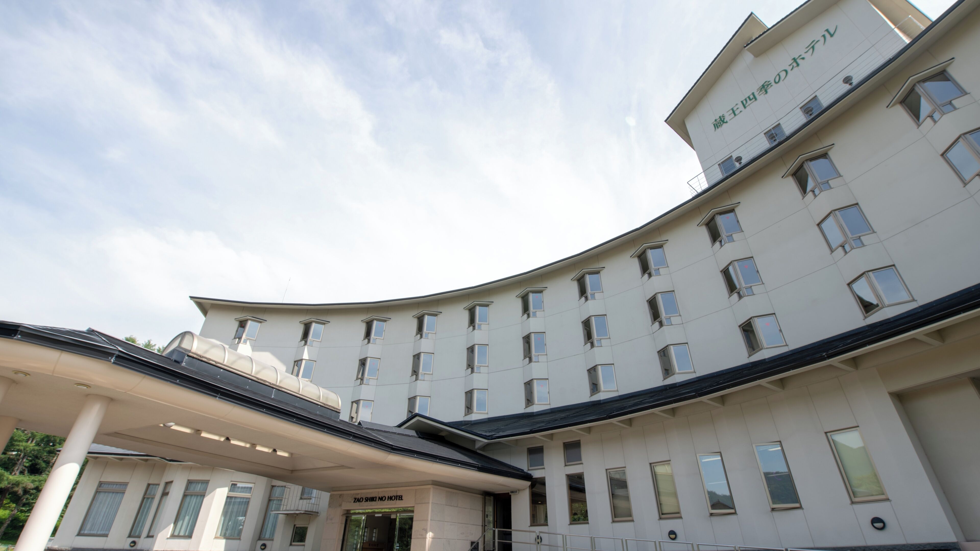 A multi-story hotel with a curved facade, multiple windows, and a covered entrance area.