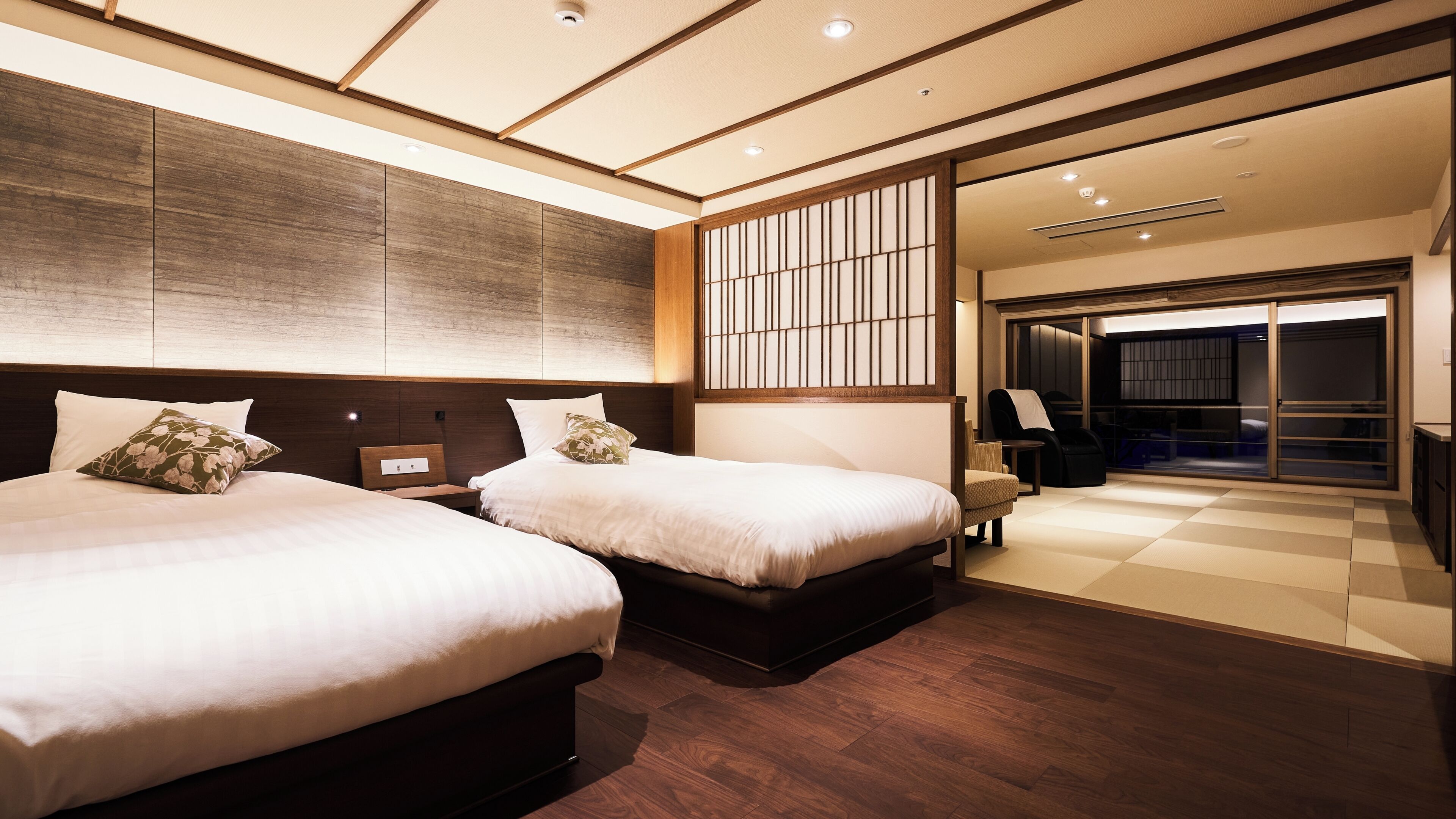 A hotel room with two beds, a large window, and a sliding door leading to a balcony.