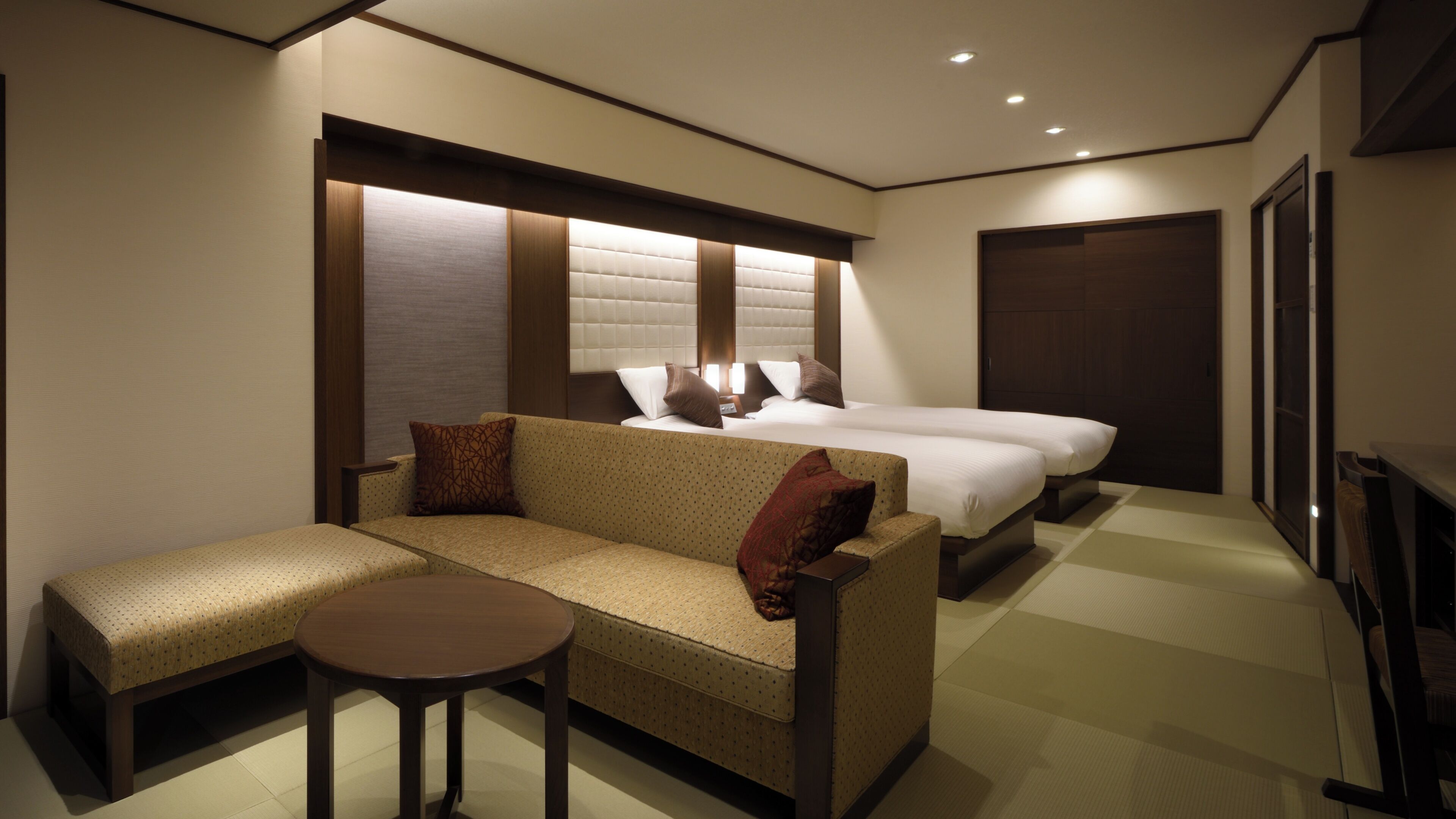 A hotel room with a sofa, a small table, a bed, and a wardrobe.
