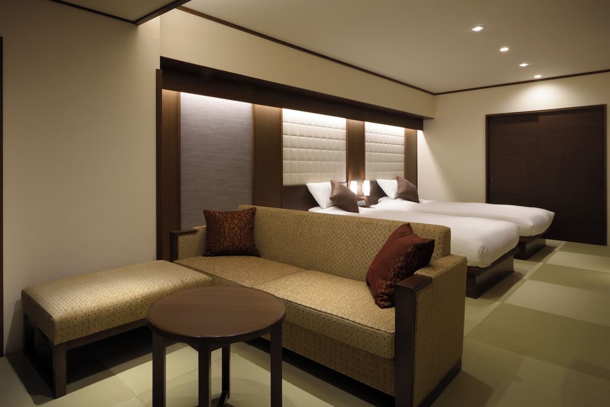 A hotel room with a sofa, a small table, a bed, and a wardrobe.