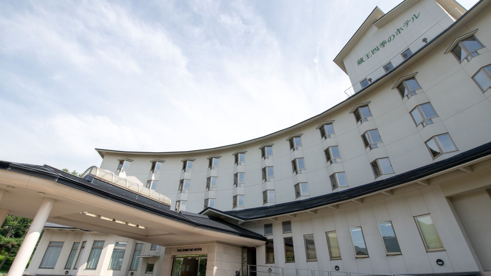 A multi-story hotel with a curved facade, multiple windows, and a covered entrance area.