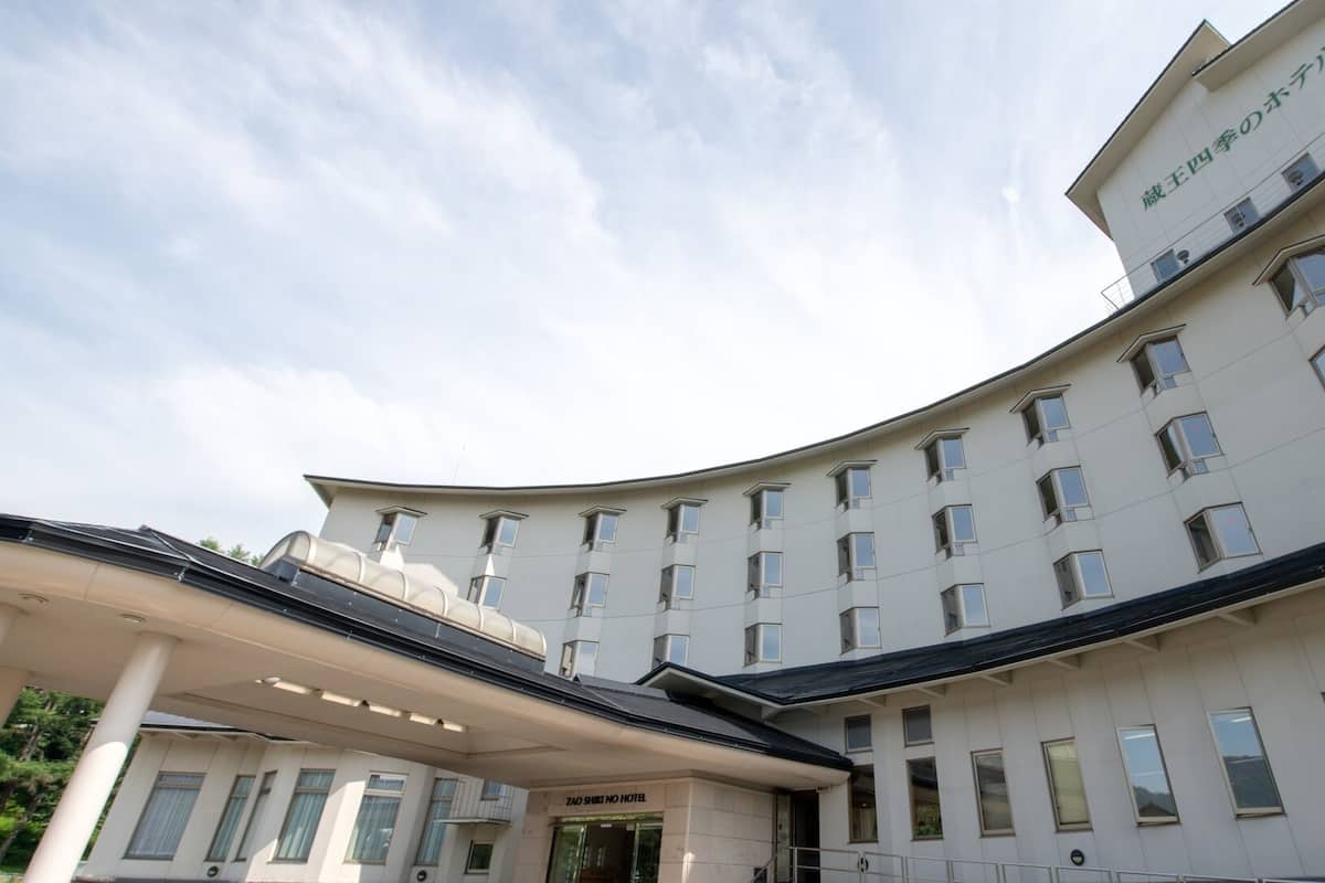 A multi-story hotel with a curved facade, multiple windows, and a covered entrance area.