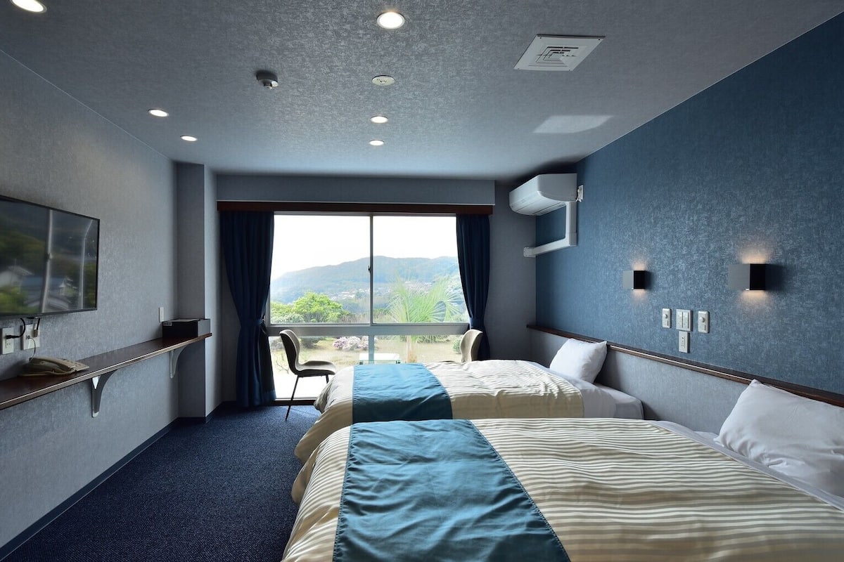 Hotelkamer met twee bedden, een televisie, een raam met uitzicht en een plafond met inbouwverlichting.
