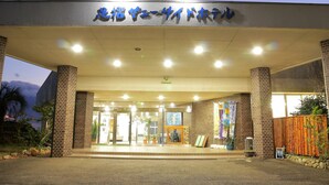 Une entrée d'immeuble avec une enseigne en japonais, des piliers en briques et des plantes en pot.