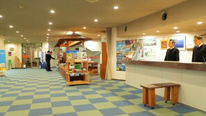 Un espace d’accueil comprenant un comptoir d’enregistrement, un banc en bois et un sol carrelé.
