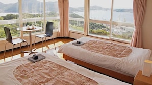 A hotel room with two beds, a dining table, chairs, and large windows with a view of a lake and mountains. - Hotel Innoshima (Onomichi)