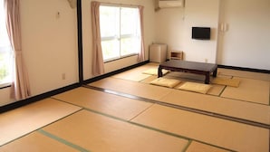 A tatami mat room with a low table, a TV, and a radiator. - Hotel Innoshima (Onomichi)