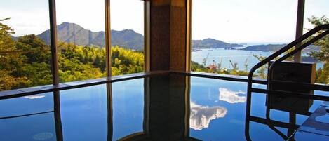 A room with a glass floor, large windows, and a view of mountains and a lake.