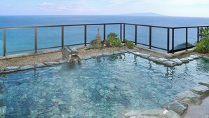 A clear pool with a stone border, a stone sculpture, and a view of the sea. - Atagawa Onsen Suiko (Higashiizu)