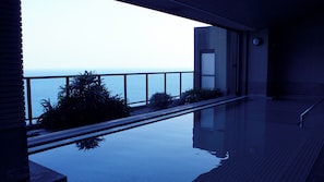 Un espace piscine moderne offrant une vue sur la mer, doté d’une balustrade en verre et d’une conception architecturale minimaliste.