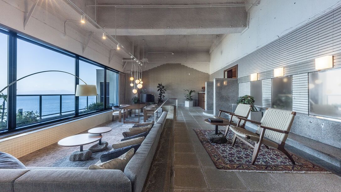 Un interior moderno con una amplia zona de estar, ventanas grandes y vistas al mar.