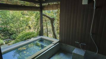 Un área de spa con hidromasaje, ducha y vistas a un jardín exuberante.