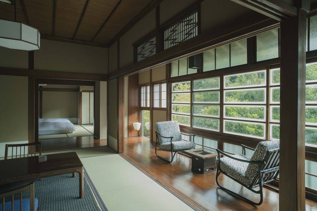 A traditional Japanese room with tatami flooring, a low table, and two patterned chairs.